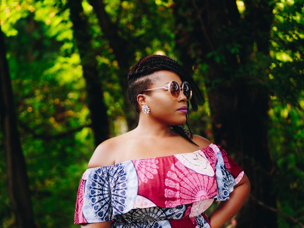 Beautiful black woman wearing sunglasses and a pink patterned blouse that falls off her shoulders.  caption: knowing lets you move through the world with confidence.  You ARE ENOUGH